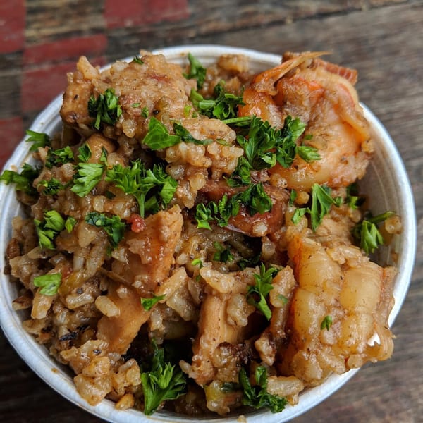 Close-up of Cajun jambalaya with rice, chicken, sausage, shrimp, and parsley in a white bowl.