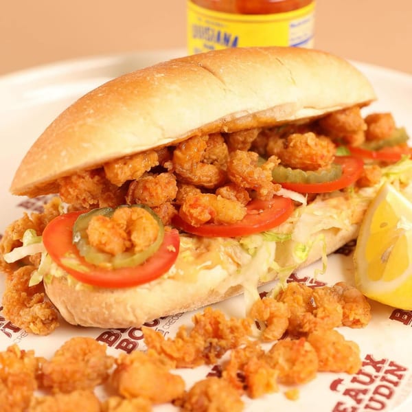 A Beaux Boudin Cajun shrimp po'boy with lettuce, tomato, pickles, and a lemon wedge.