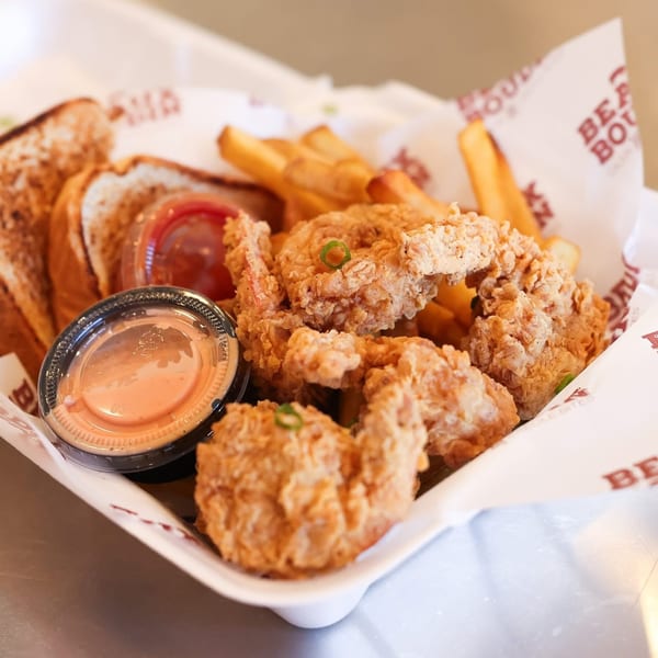 A basket of BEAUX BOUDIN's fried shrimp, fries, toast, and dipping sauces.