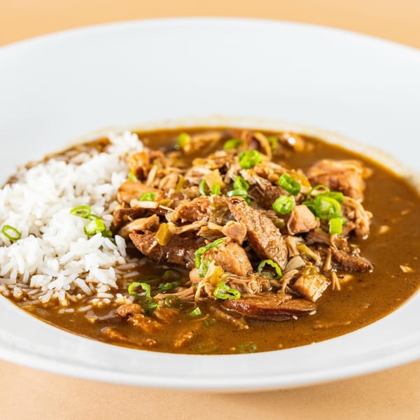 A bowl of Beaux Boudin's Cajun gumbo with rice, chicken, sausage, and green onions.
